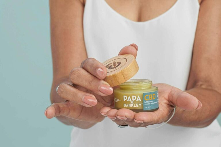 A happy customer opening the lid on a Papa & Barkley Cannabis Wellness Product