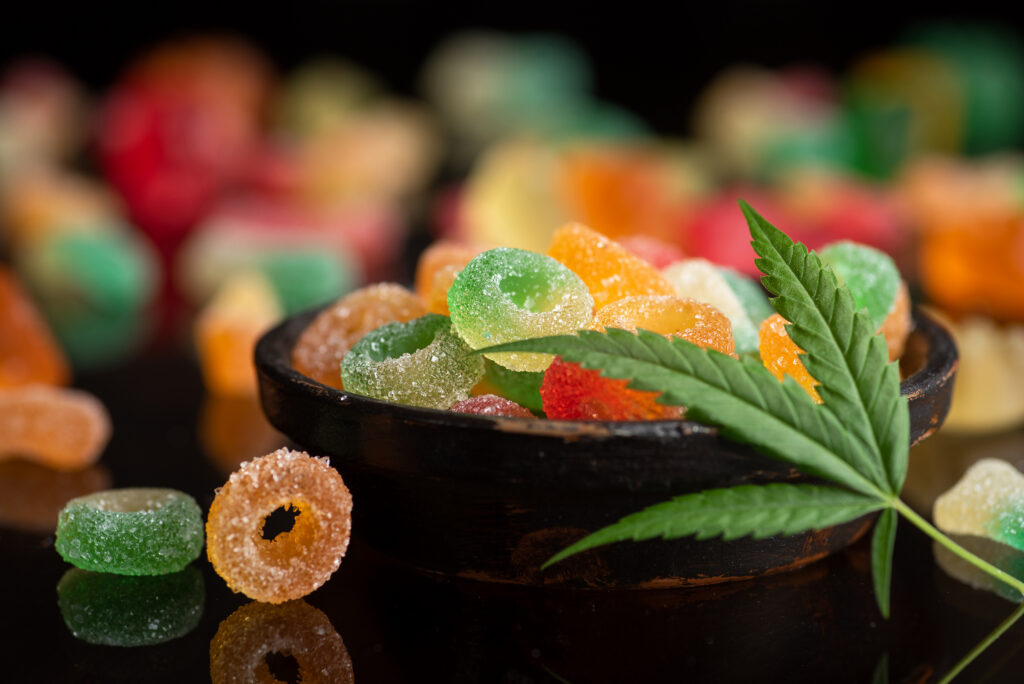 Colored candy gelatin in a black bowl with marijuana leaves - URBN Leaf Not sure which cannabis method is right for you? We’re here to help you explore gummies, vapes, and flower — your way.
